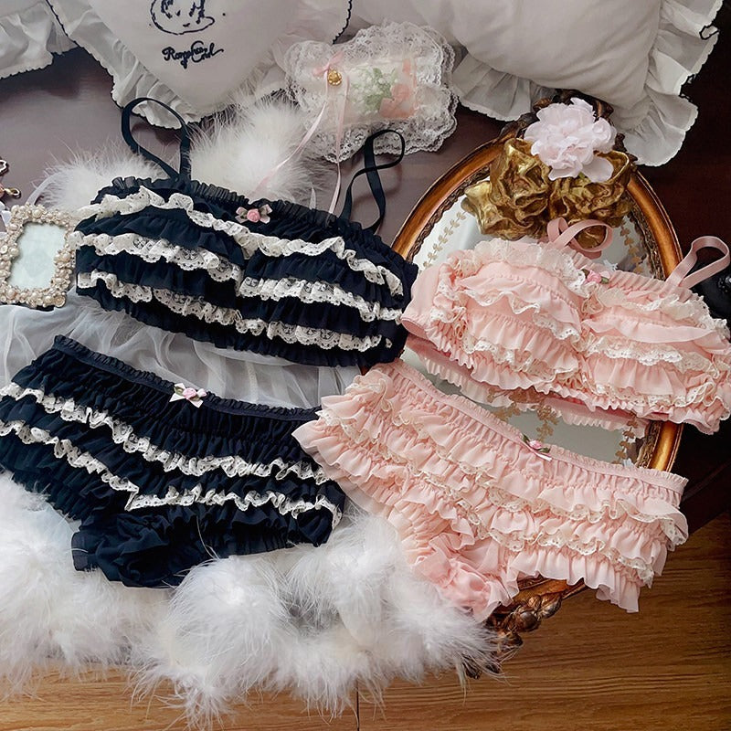 Pair of black and pink ruffled bloomers on a decorative surface with flowers and ribbons.