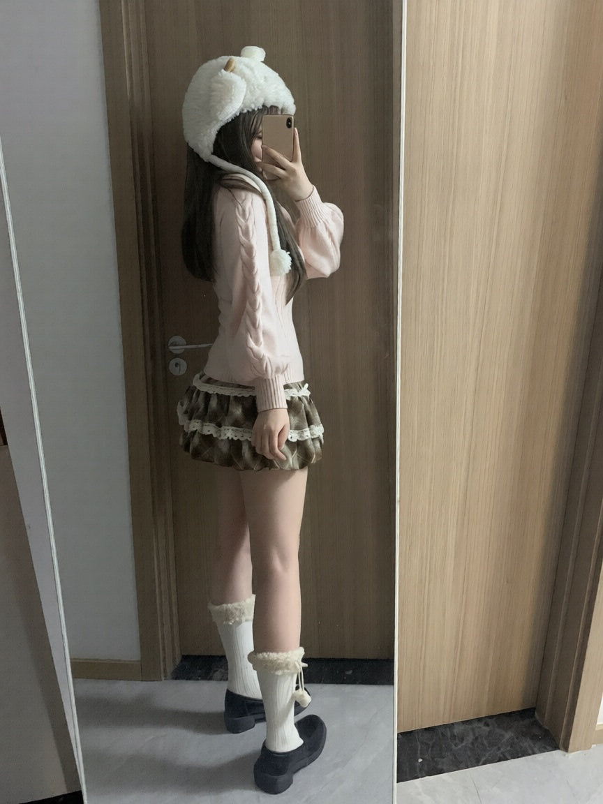 Person wearing a white knit sweater, patterned skirt, and white boots in front of a mirror.