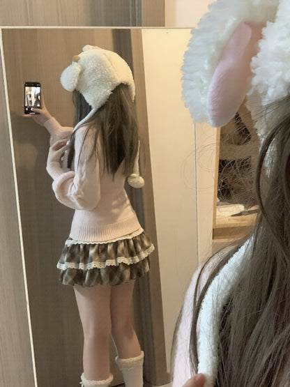 Person wearing a white sweater, skirt, and bunny ears in front of a mirror.