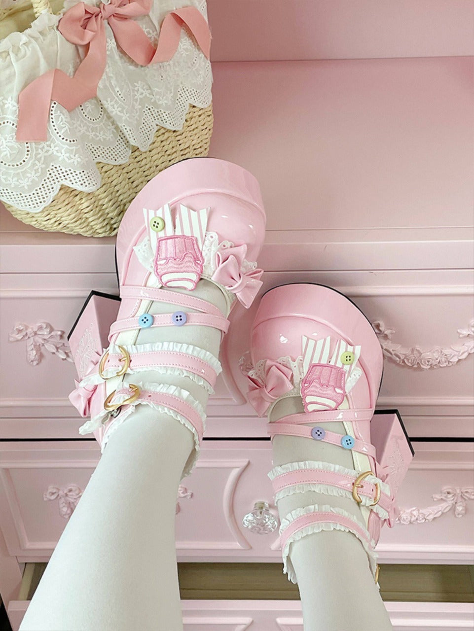 Pink high heels with decorative cute cupcake elements on a pink background