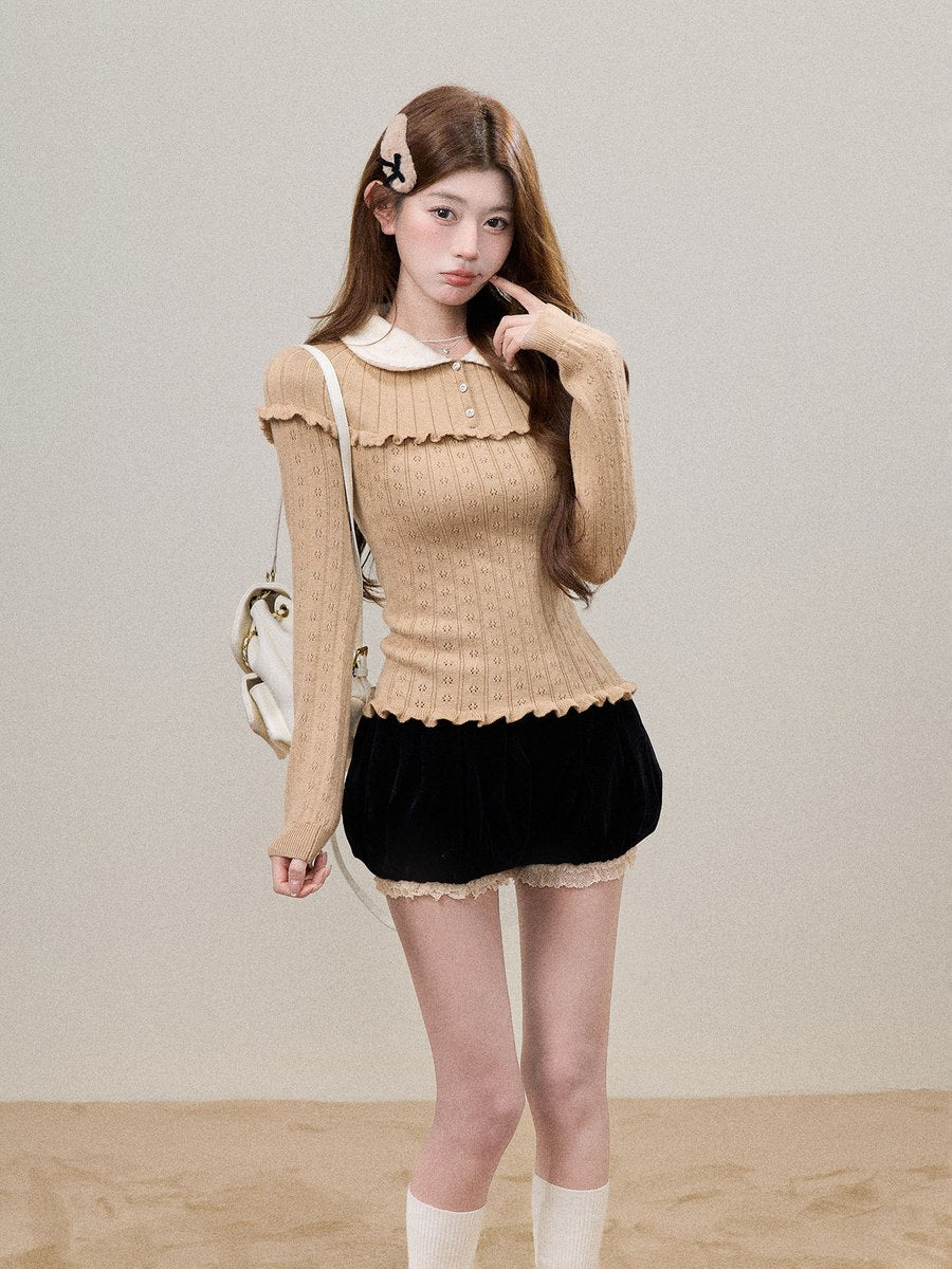 A young woman models a beige ribbed long-sleeve top with a white Peter Pan collar and scalloped edges, paired with a black velvet mini skirt and white socks, against a neutral beige background.