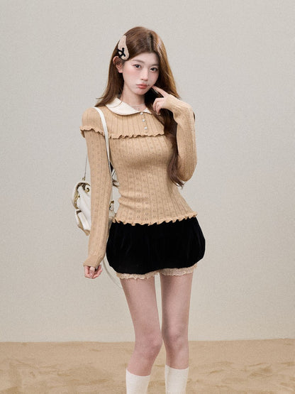 A young woman models a beige ribbed long-sleeve top with a white Peter Pan collar and scalloped edges, paired with a black velvet mini skirt and white socks, against a neutral beige background.