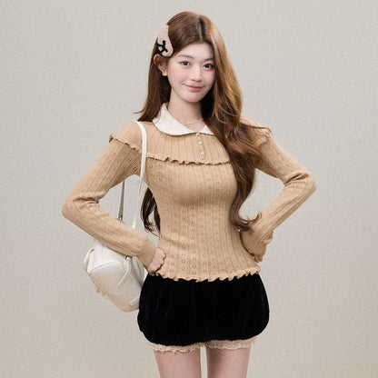 A young woman models a beige ribbed knit long-sleeve top with a ruffled collar and hem, paired with a black velvet mini skirt with a lace hem. She is carrying a white shoulder bag and wearing white socks, standing against a neutral beige background.
