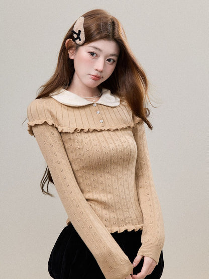 A young woman wearing a beige ribbed knit long-sleeve sweater with a cream Peter Pan collar and ruffled trim, paired with a black skirt. She is posing against a neutral light gray background.