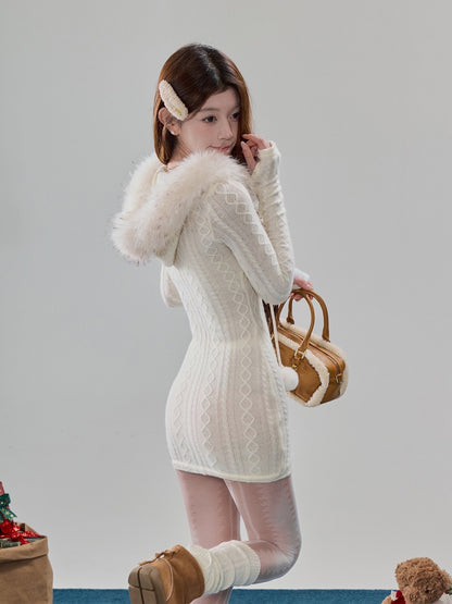 A woman models a white cable-knit mini dress with a fluffy faux-fur collar, paired with sheer pink tights, brown boots, and a brown and white handbag against a plain light gray background.