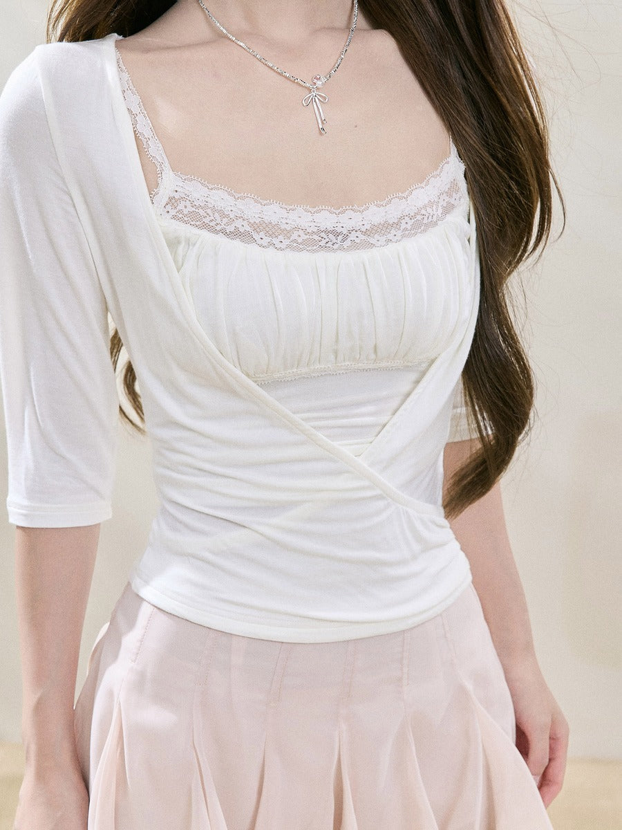 A woman wearing a white ruched camisole top with lace trim at the neckline, layered under a white open-front cardigan, paired with a pale pink skirt.