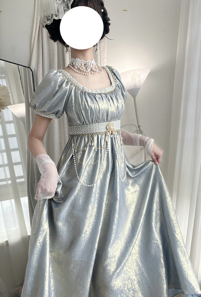 Person wearing a silver gown with gloves and a tiara in a softly lit room.