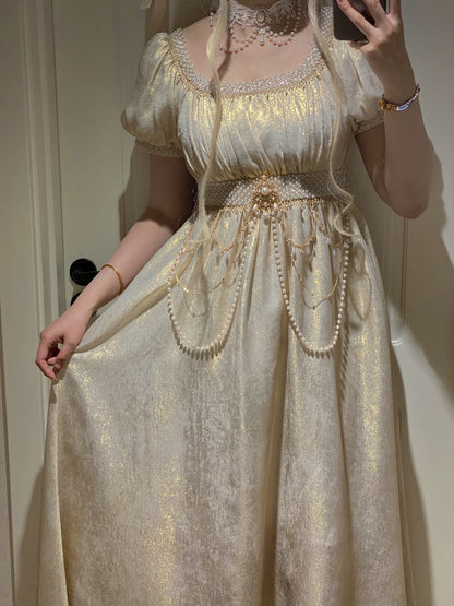 Person wearing a gold and white dress with decorative elements, standing against a neutral background.