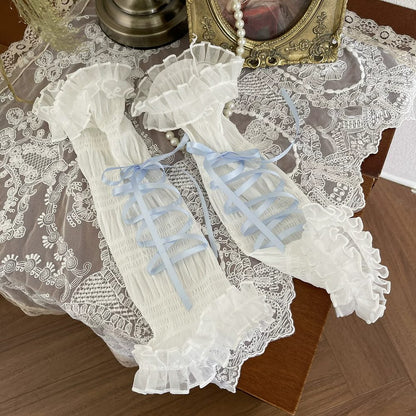 Pair of lace gloves with blue ribbons on a lace tablecloth.