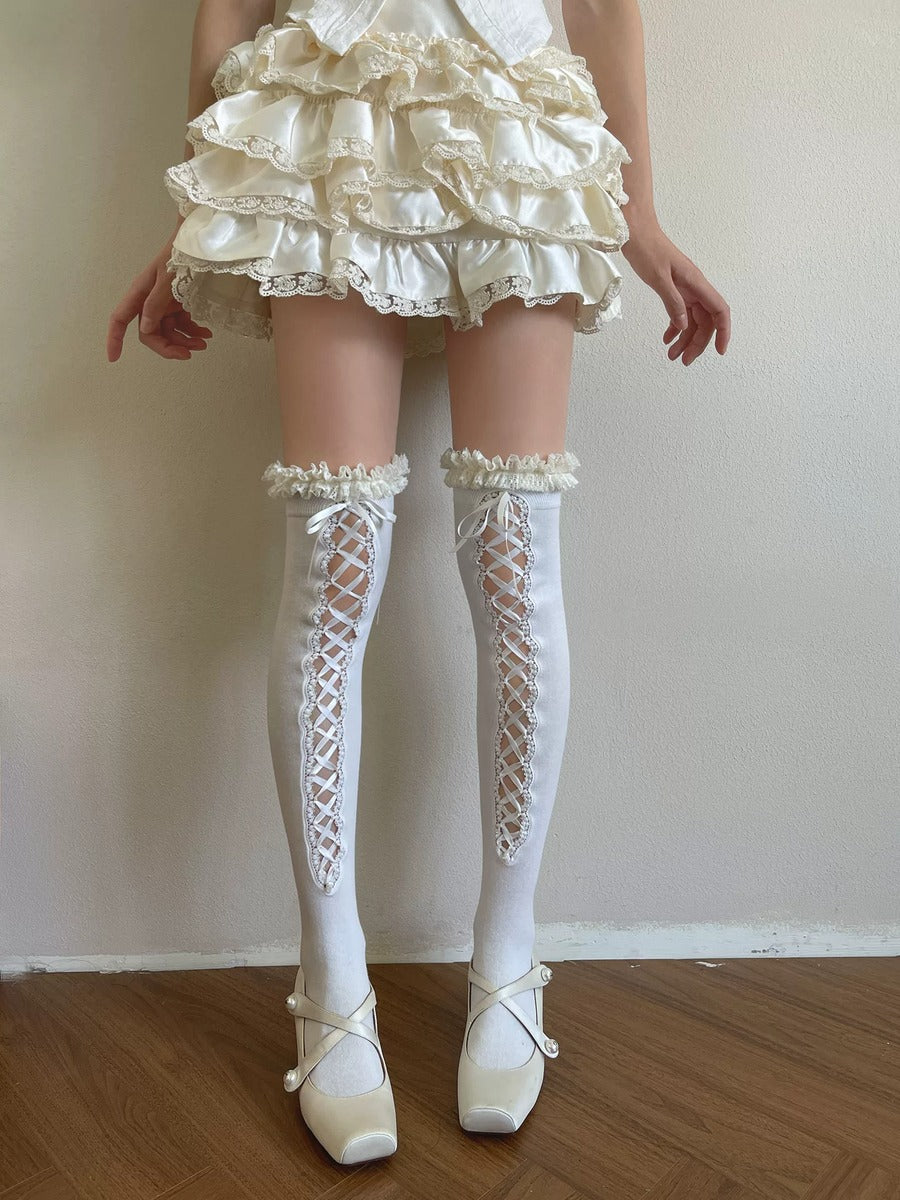 Person wearing a white lace dress, stockings, and shoes on a plain background