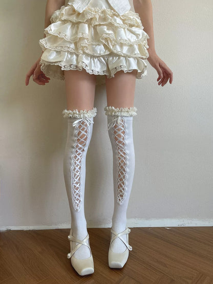 Person wearing a white lace dress, stockings, and shoes on a plain background