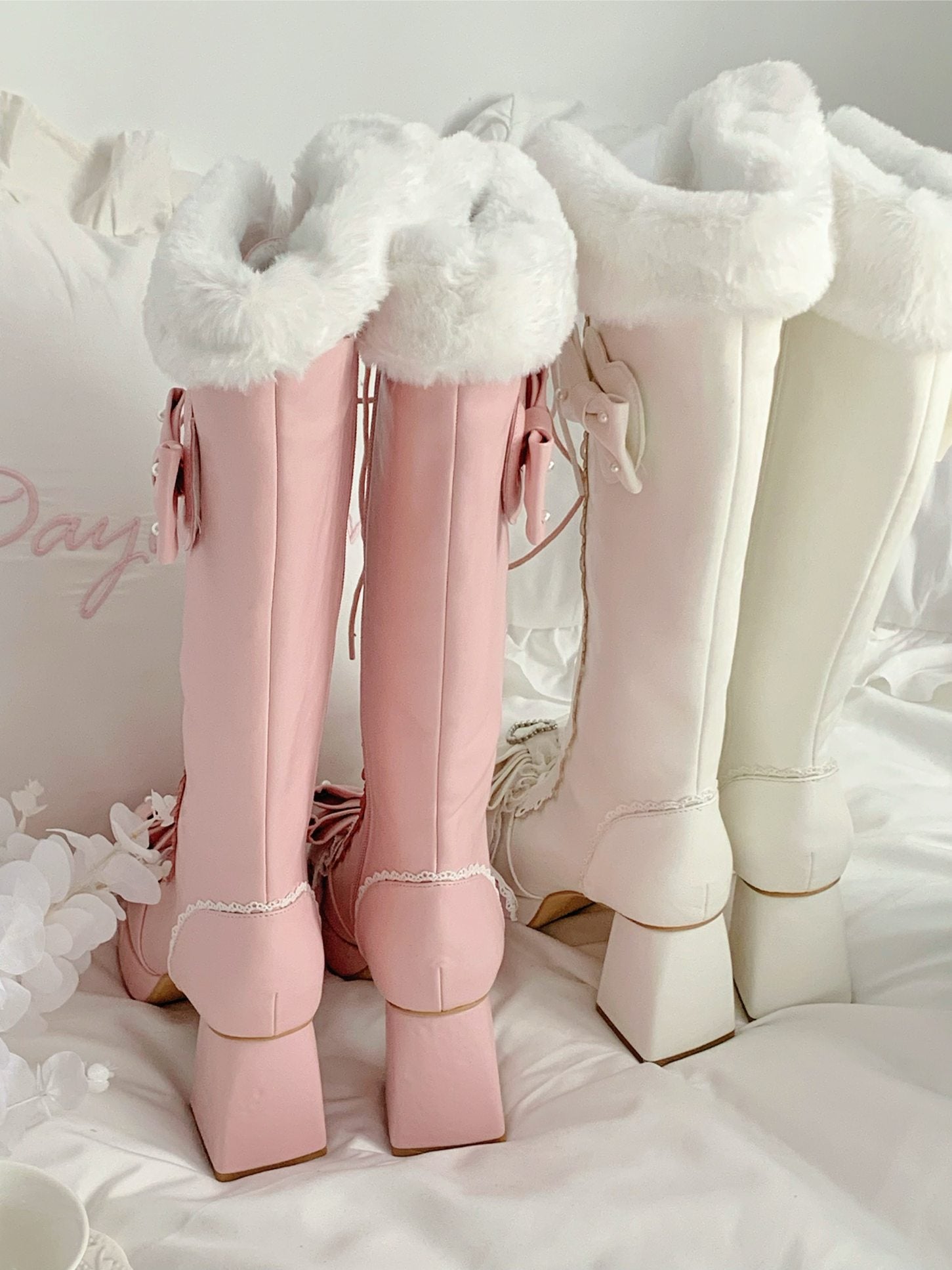 Pair of pink knee-high boots with white fur trim on a white background