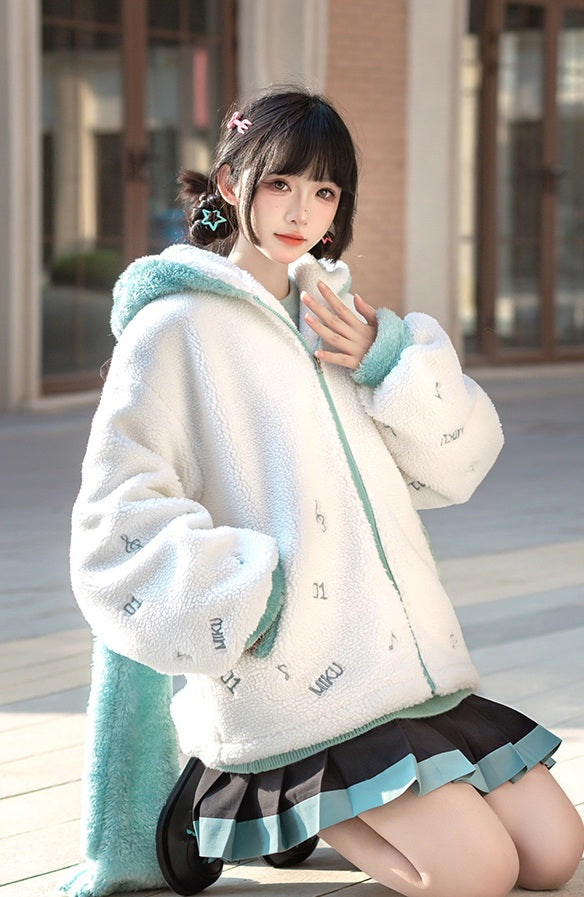 Person wearing a white and green jacket with fluffy hood, sitting on a bench.