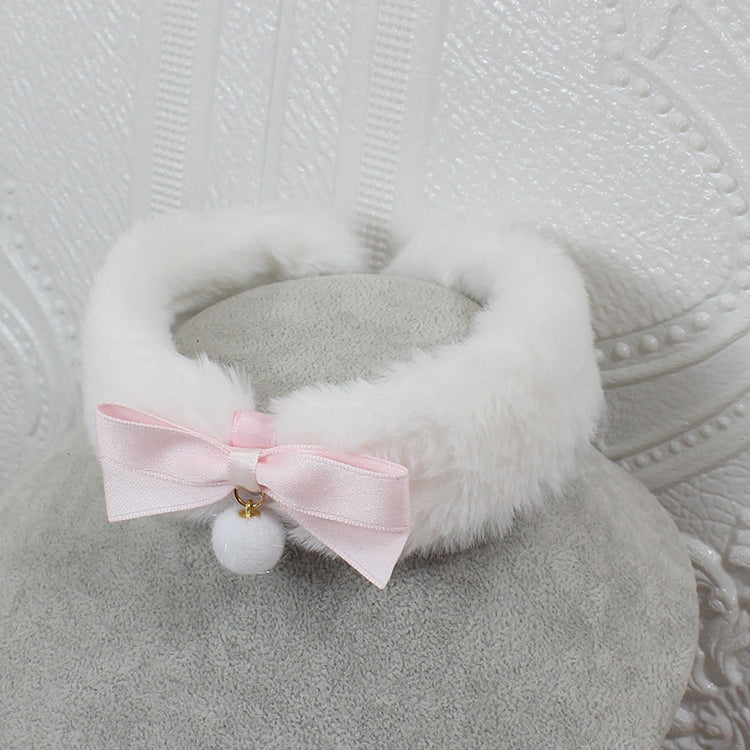 White fluffy headband with a pink bow and white pom-pom on a textured gray background