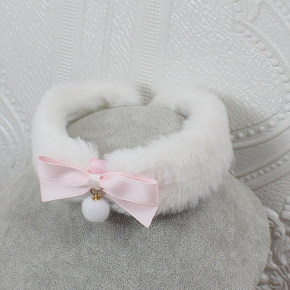 White fluffy headband with a pink bow and white pom-pom on a textured gray background