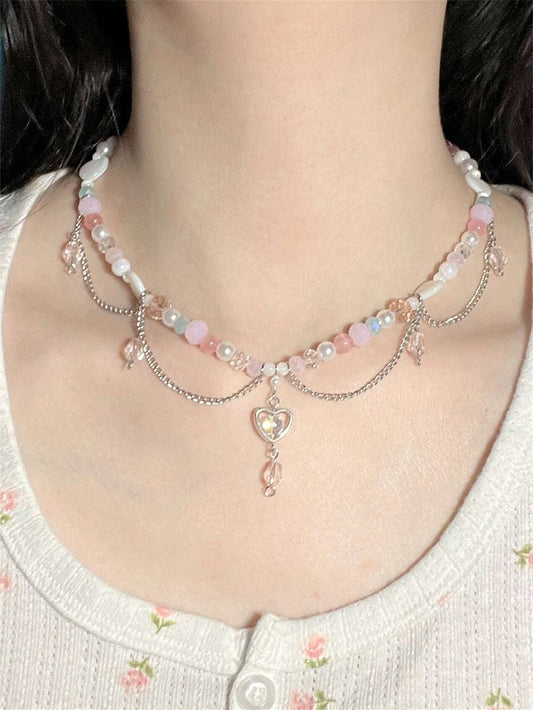Necklace with heart-shaped pendant and pink beads worn by a person