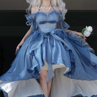 Person wearing a blue dress with ruffles and holding flowers against a dark background