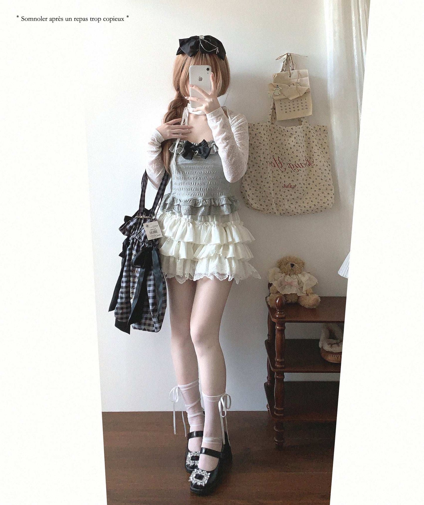 Person taking a mirror selfie wearing a layered outfit with a teddy bear and bag in the background.