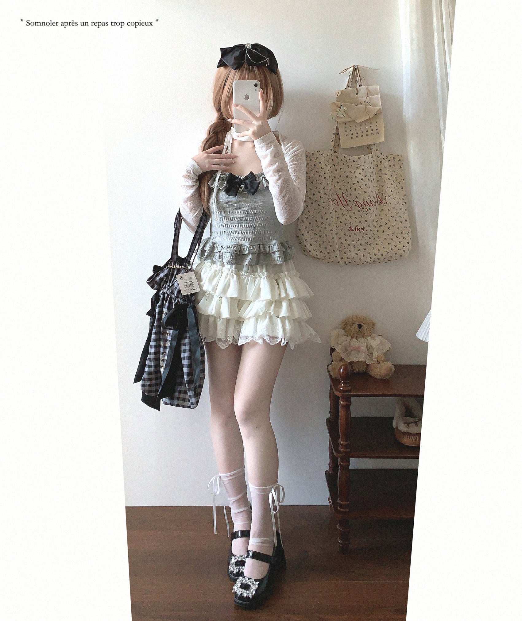 Person taking a mirror selfie wearing a layered outfit with a teddy bear and bag in the background.