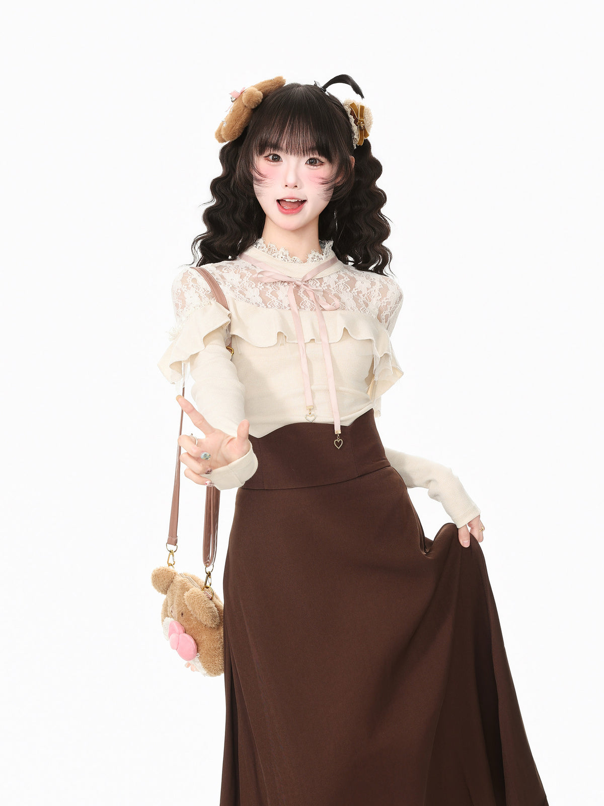 A young woman modeling a cute Lolita-style outfit consisting of a cream lace blouse with ruffles, a brown high-neck skirt, and a brown teddy bear hair accessory, holding a matching teddy bear shoulder bag against a plain white background.