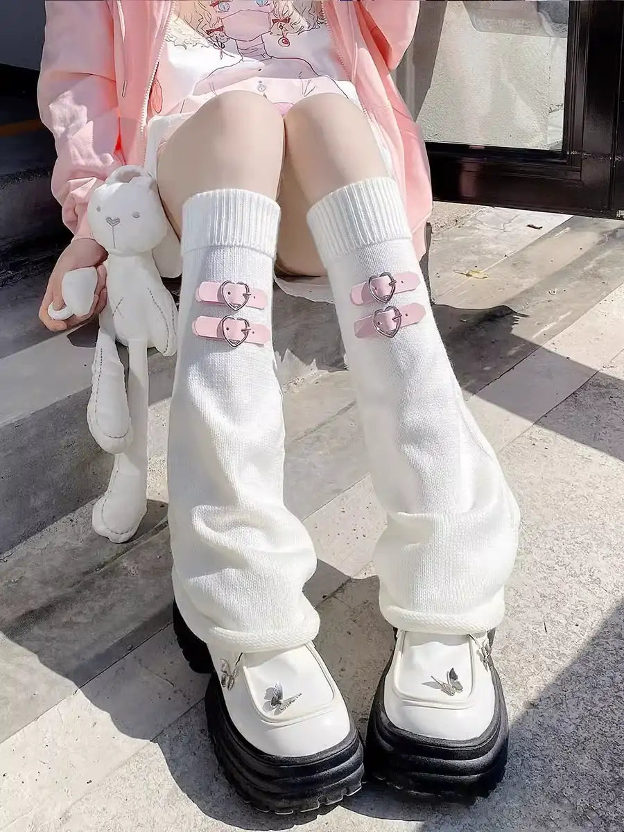 Person wearing white knee-high socks with pink buckles and black shoes on a stone surface.