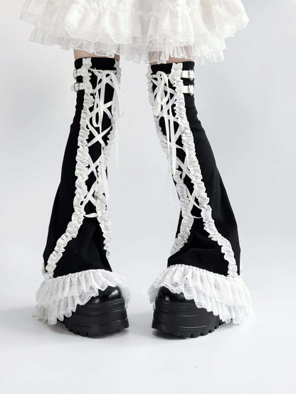Black leg warmers with white lace and ruffles worn with a white skirt on a white background