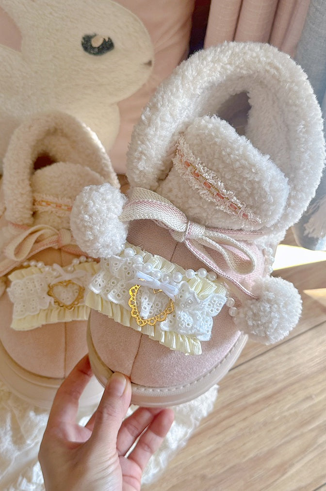 Pink shoes with decorative elements held by a hand, with a soft focus background.