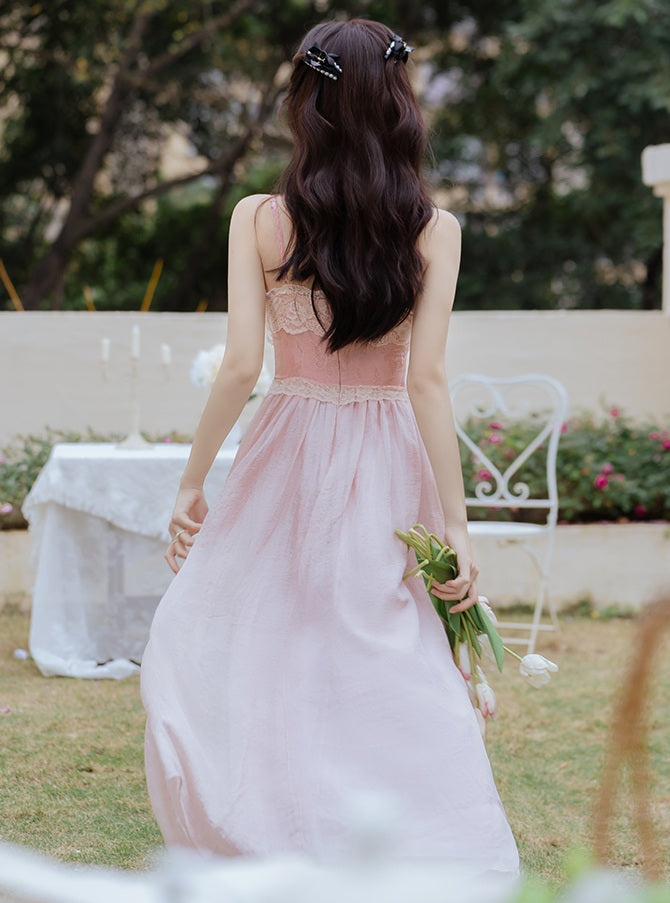 Woman in a pink dress holding flowers in an outdoor setting