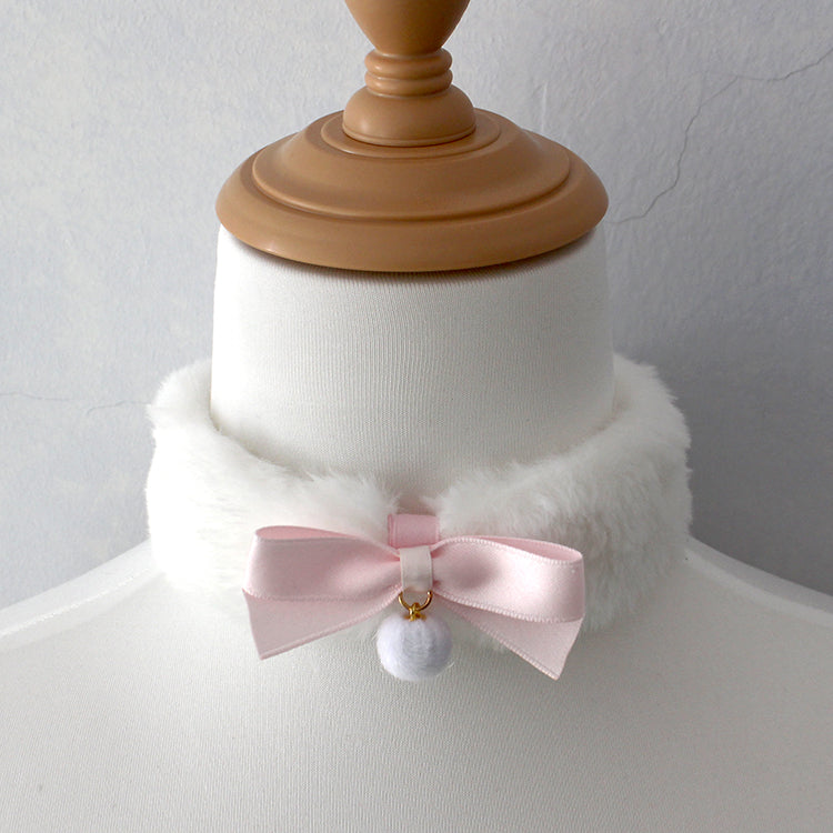 Mannequin head with a white fur collar and pink bow accessory on a plain background