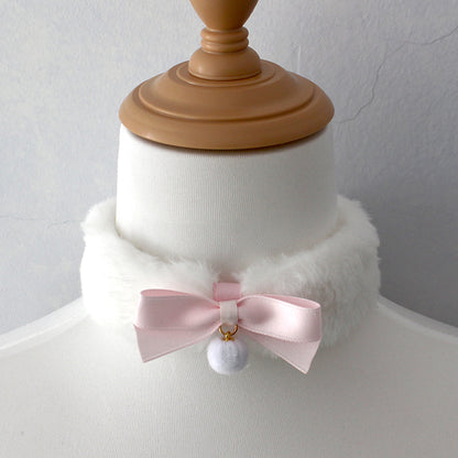 Mannequin head with a white fur collar and pink bow accessory on a plain background