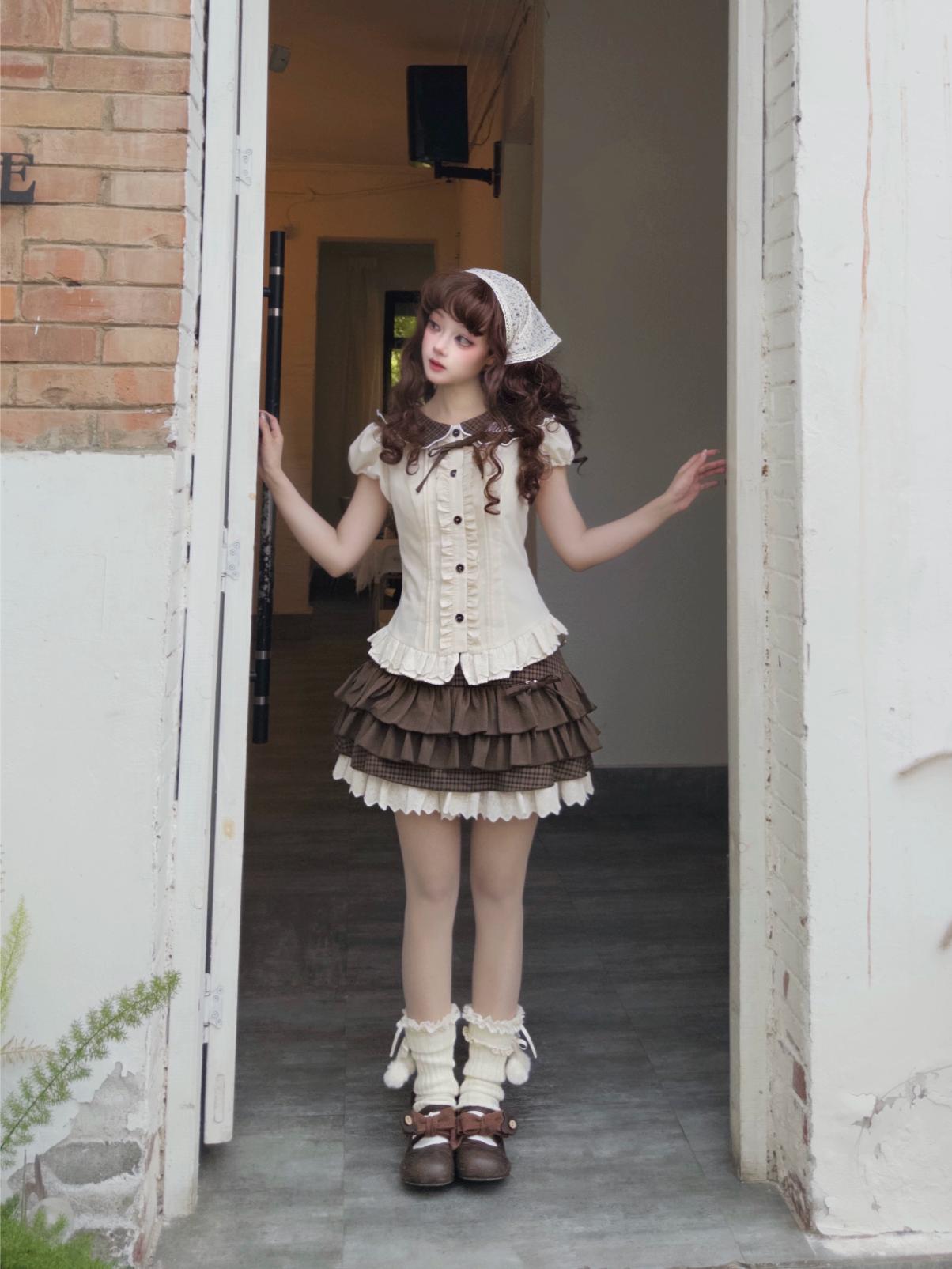 Woman in a white and brown dress standing in an open doorway.