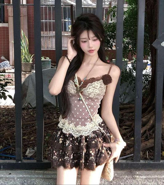 Woman in a lace dress standing behind a metal gate with plants and buildings in the background