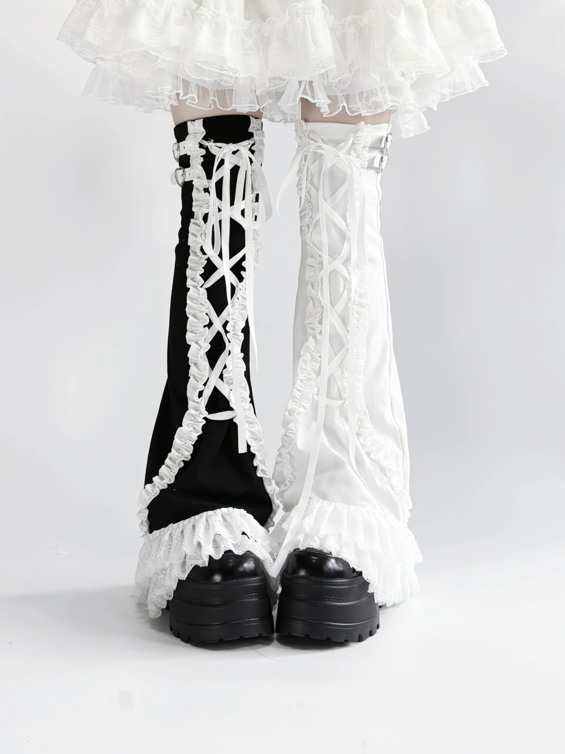 Black and white lace-up leg warmers with ruffled details on a plain background