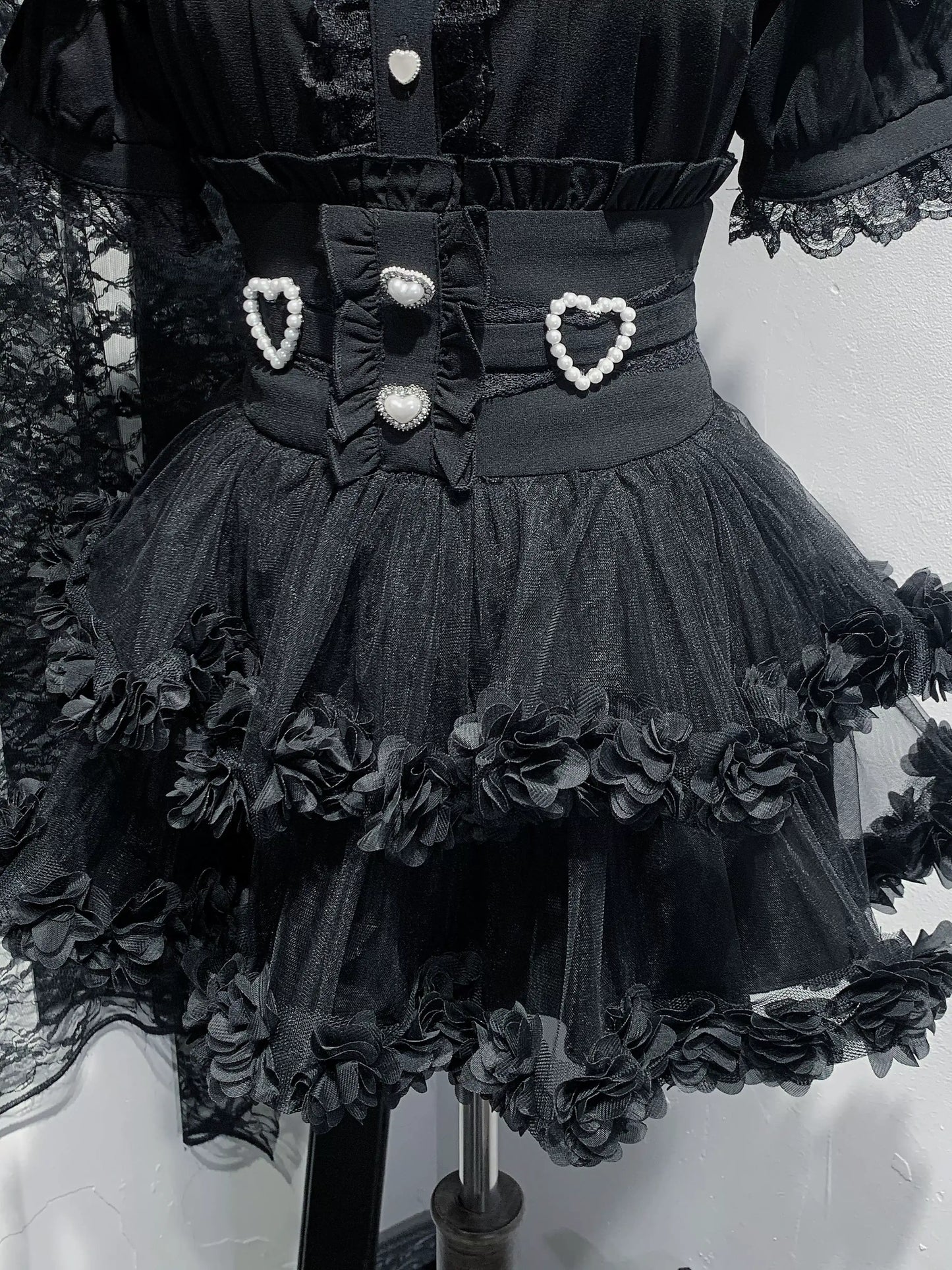 Black dress with floral details and heart-shaped buttons on a mannequin.