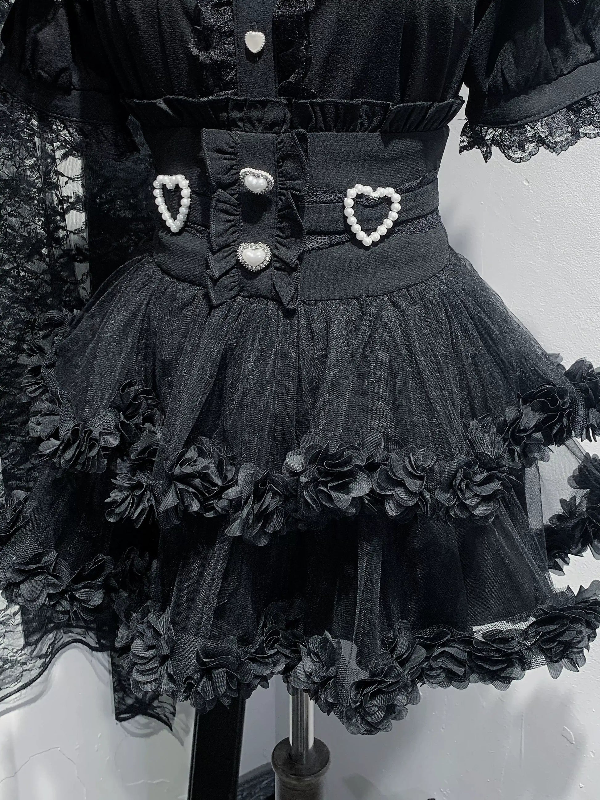 Black dress with floral details and heart-shaped buttons on a mannequin.
