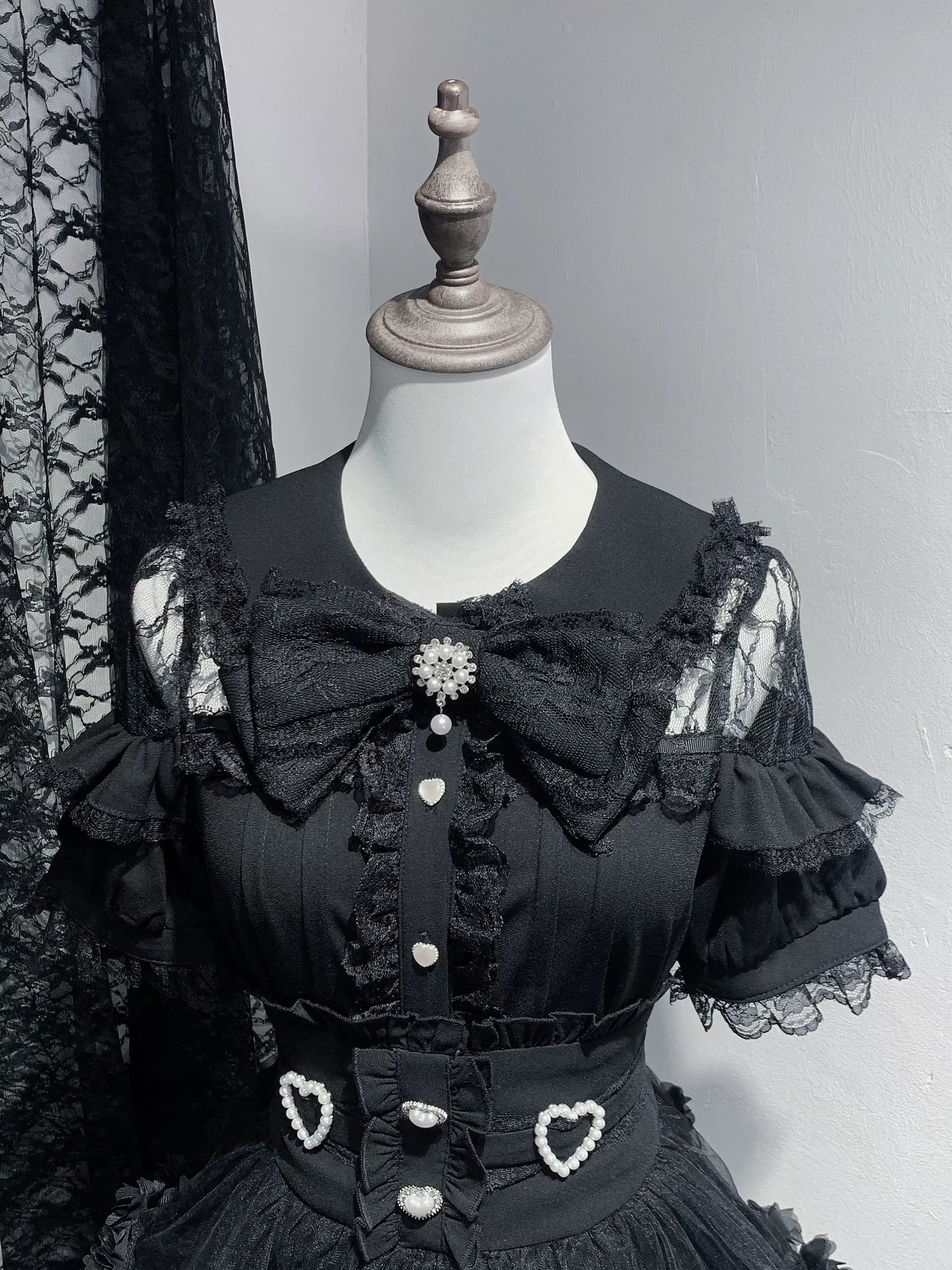 Black lace dress on a mannequin against a gray background