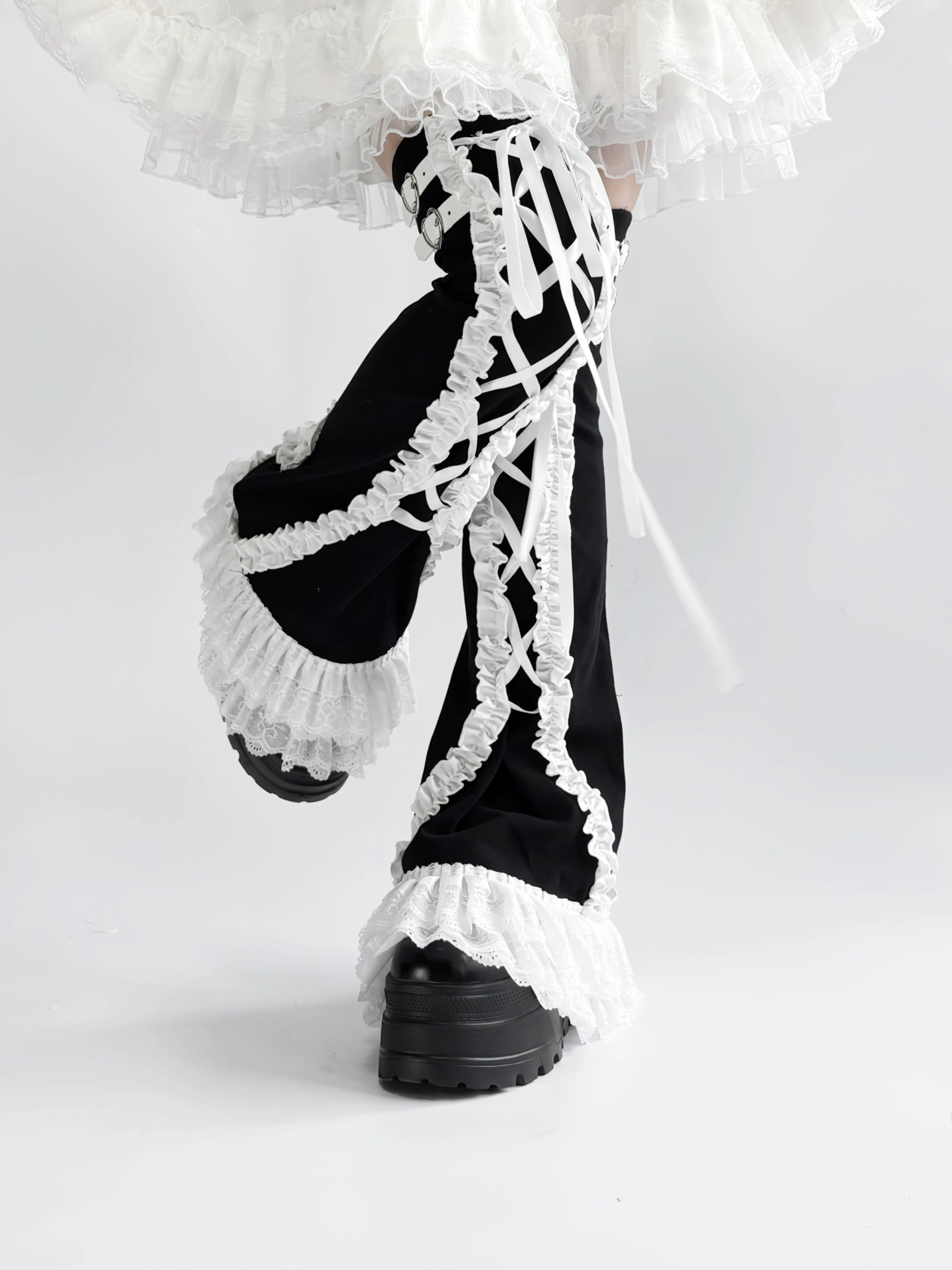 Black and white lace-up leg warmers with ruffled details on a white background