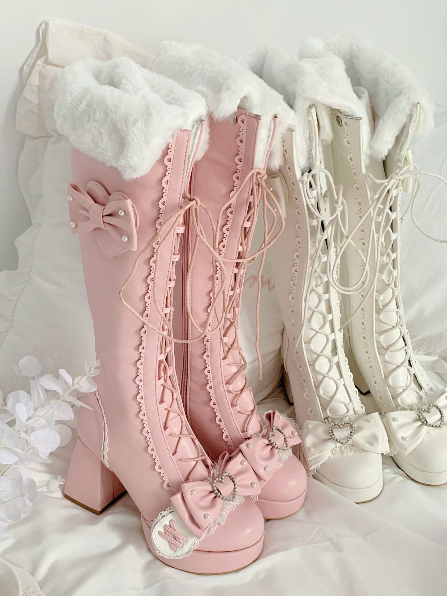 Pair of pink and white lace-up boots with decorative elements on a white background