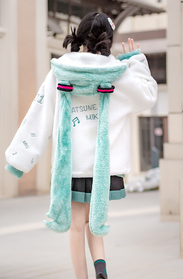 Person wearing a white coat with a green scarf in an urban setting