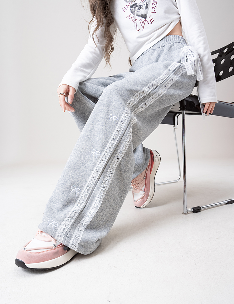 Person wearing gray sweatpants with white stripes sitting on a chair.