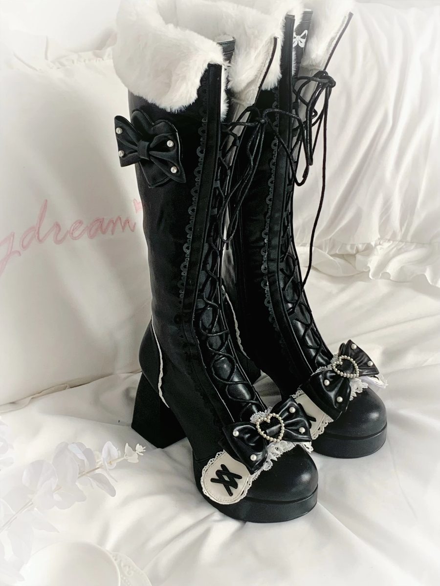 Black knee-high boots with decorative elements on a white background