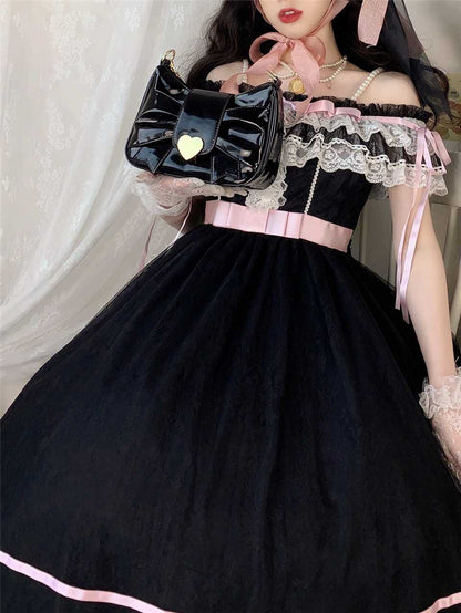 A person wearing a black Lolita-style ballgown dress with pink ribbon accents, white lace trim, and a pearl necklace, holding a shiny black handbag with a gold heart detail.