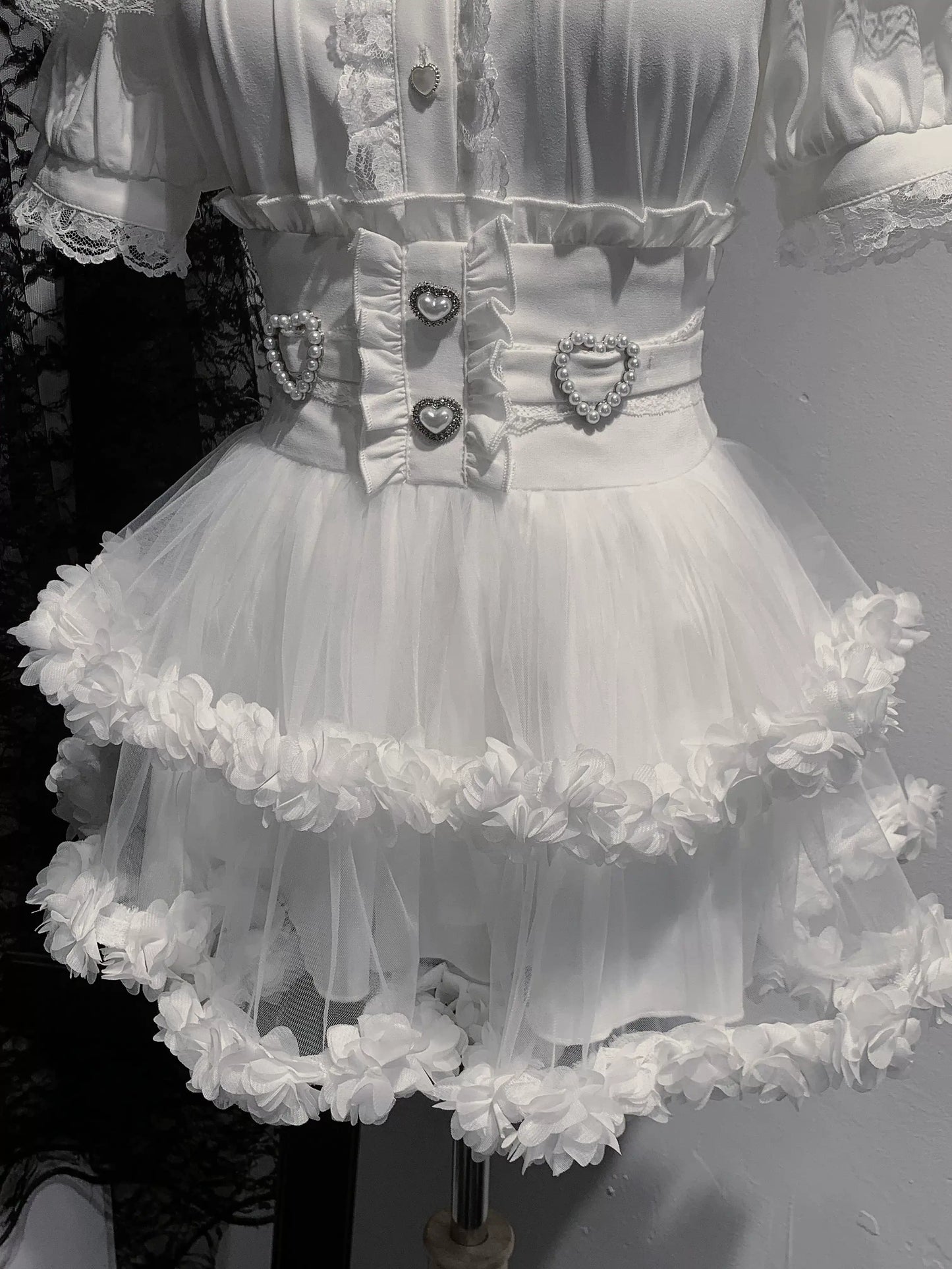White dress with ruffled skirt and decorative belt on a mannequin.
