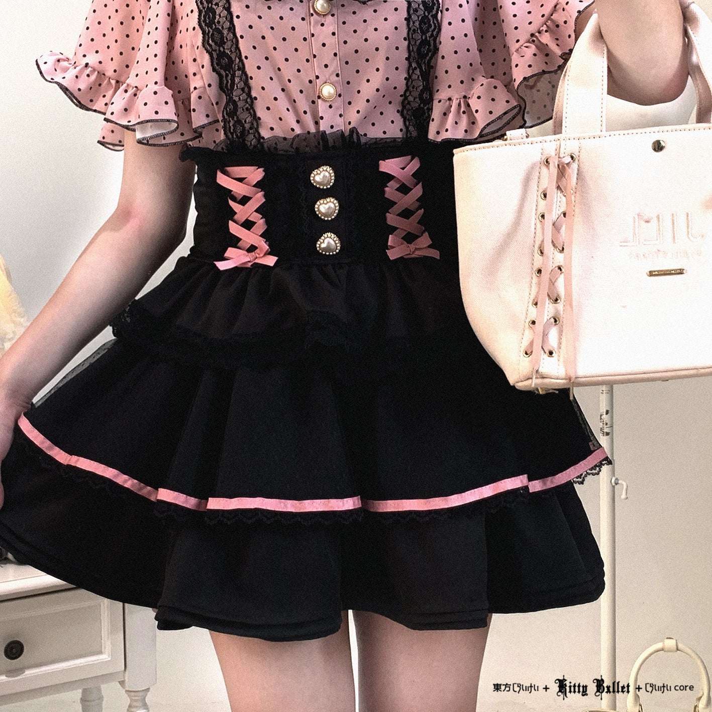 Person wearing a jirai kei black skirt with pink accents and a pink top, holding a white handbag.