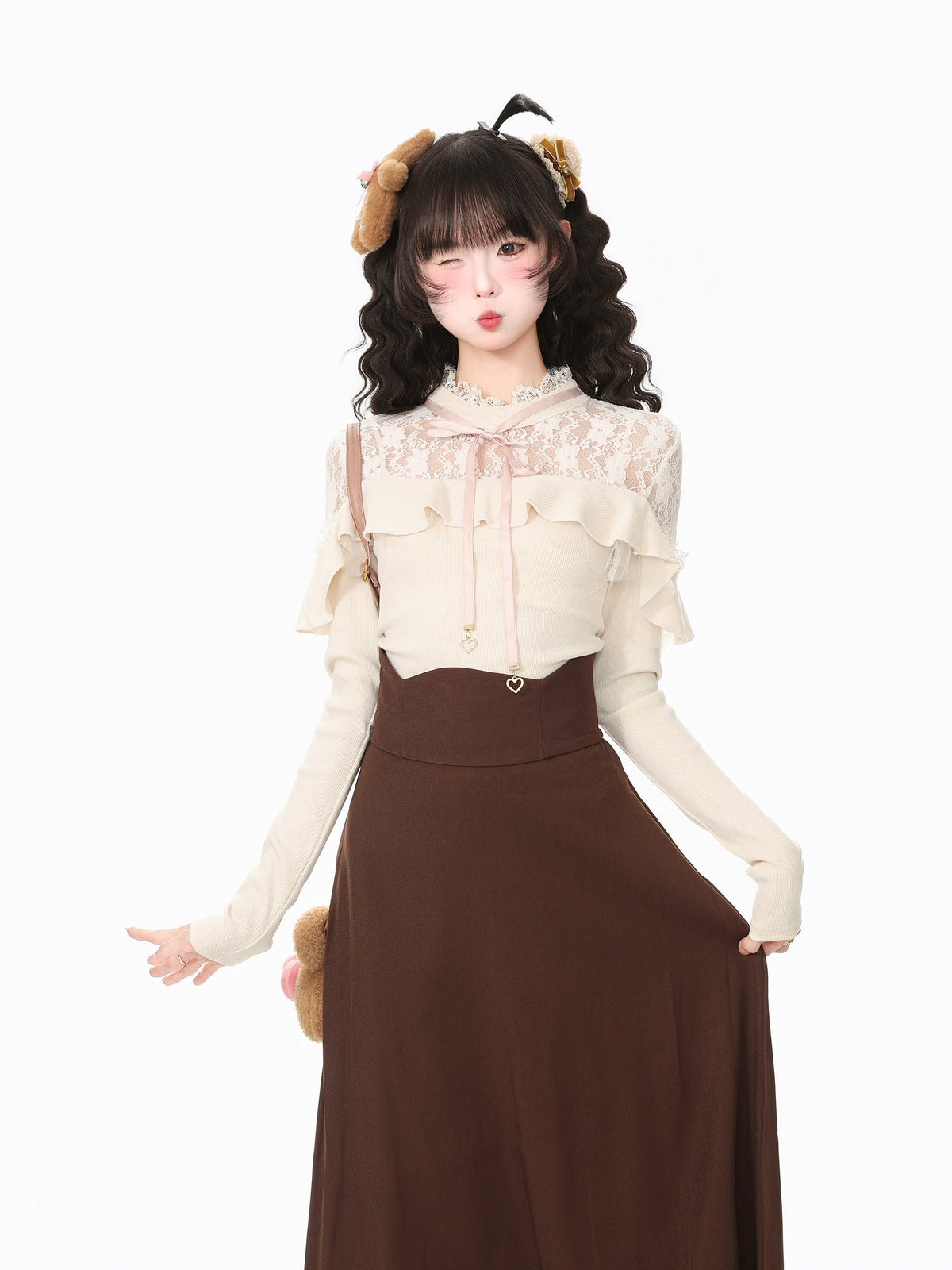 A young woman modeling a cream and brown outfit against a plain white background. She is wearing a cream long-sleeve blouse with lace and ruffle details, paired with a high-waisted brown skirt.