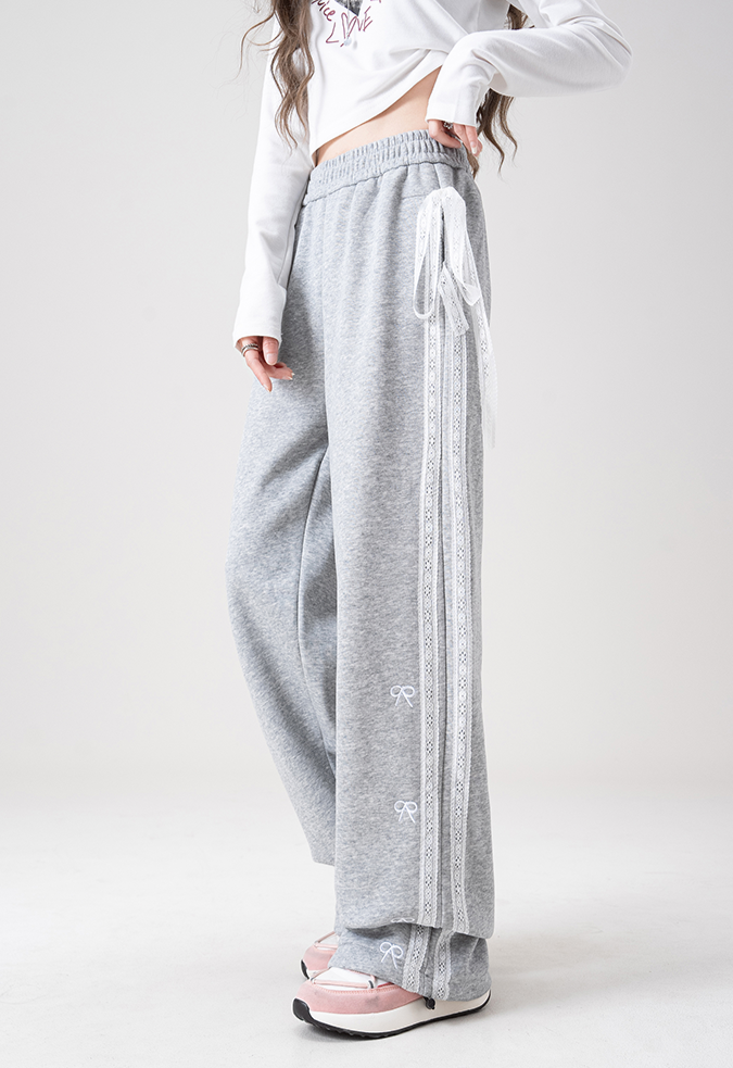 Person wearing gray sweatpants with white stripes on a white background