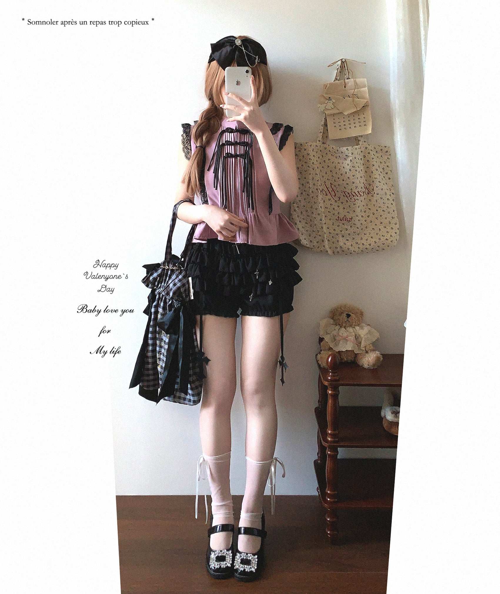 Person in a pink top and black skirt standing in a room with a teddy bear and bags.