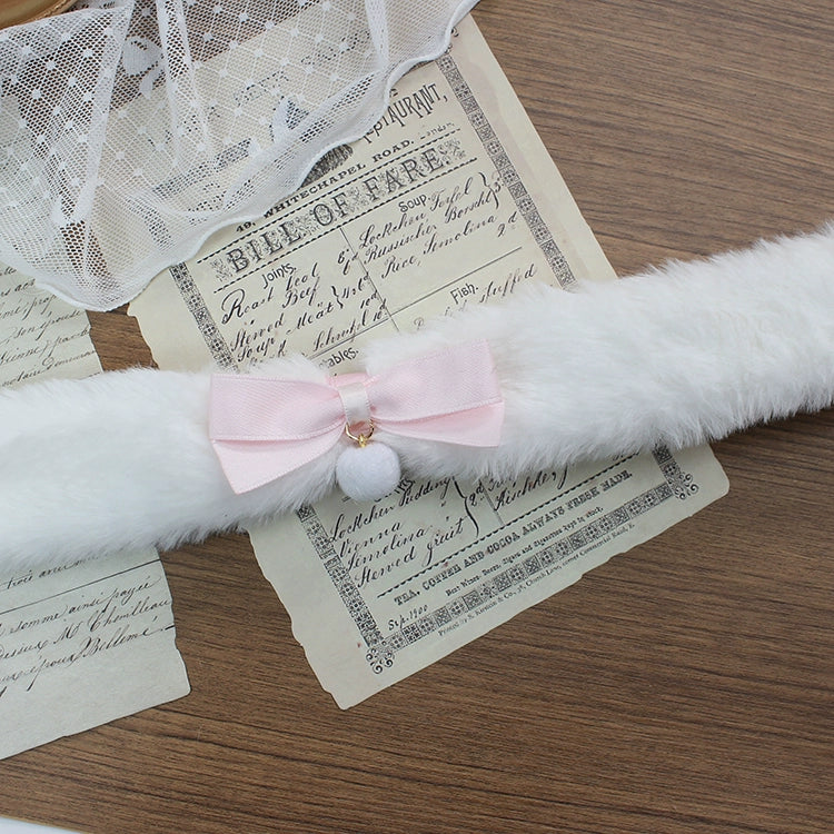 White fluffy cat toy with a pink bow on top of vintage papers.