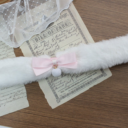 White fluffy cat toy with a pink bow on top of vintage papers.