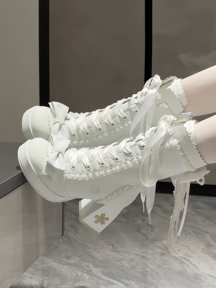 White high-heeled shoes with lace details on a neutral background